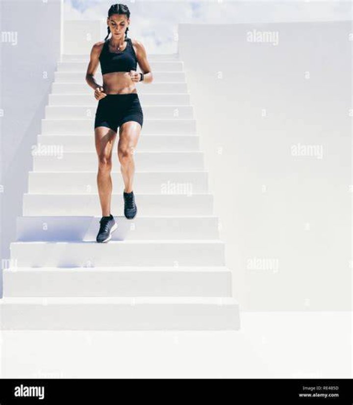 a woman running down the street wearing black shorts and a sports bra